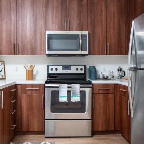 Pet-Friendly Apartments in San Jose CA - LINQ - Kitchen with Wood-Style Flooring, Brown Cabinets, White Quartz Countertops, and Stainless Steel Appliances